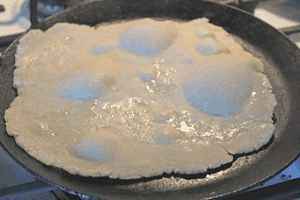 Roti cooking on tava, rising in some areas
