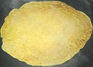 Chickpea roti is flipped to cook the other side