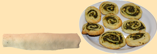 Dough shaped into a rectangle, filled with spinach in one row, then rolled